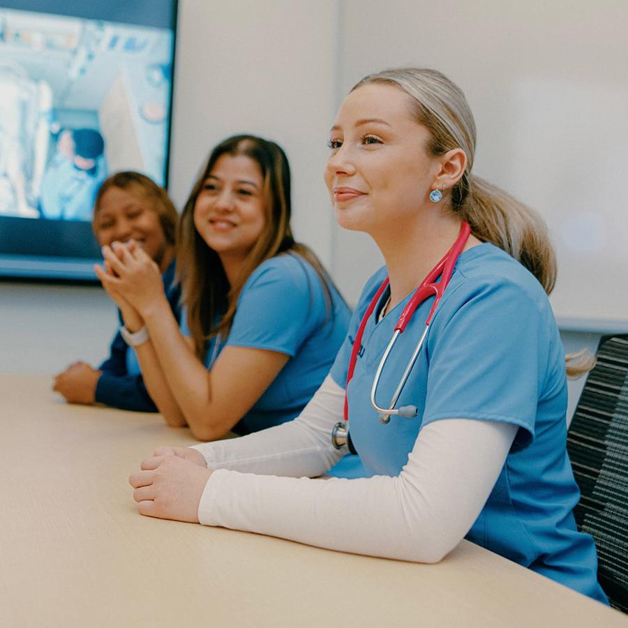 nursing students around conference table with image on presentation screen